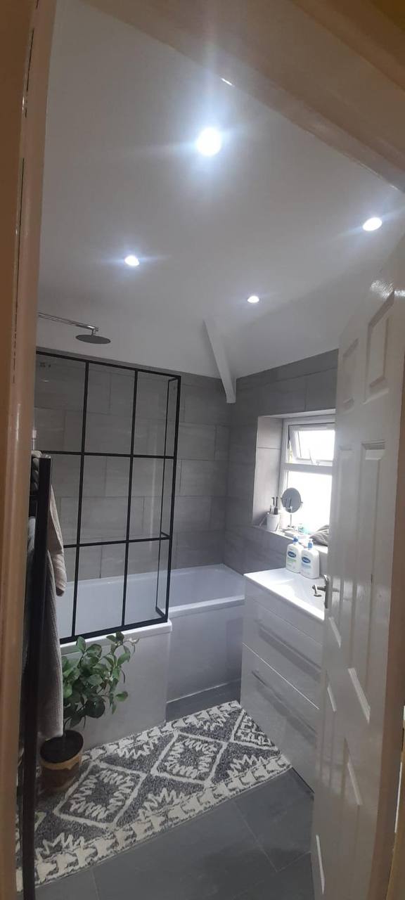 Bright bathroom refurbishment with black Crittall-style shower screen, gloss vanity and grey tiling
