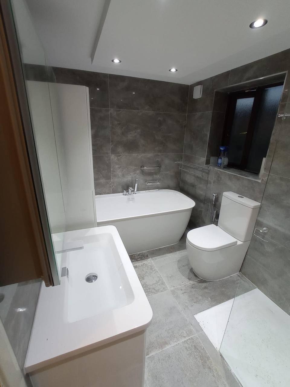 Luxury bathroom with freestanding bath, marble-effect grey tiling and walk-in shower