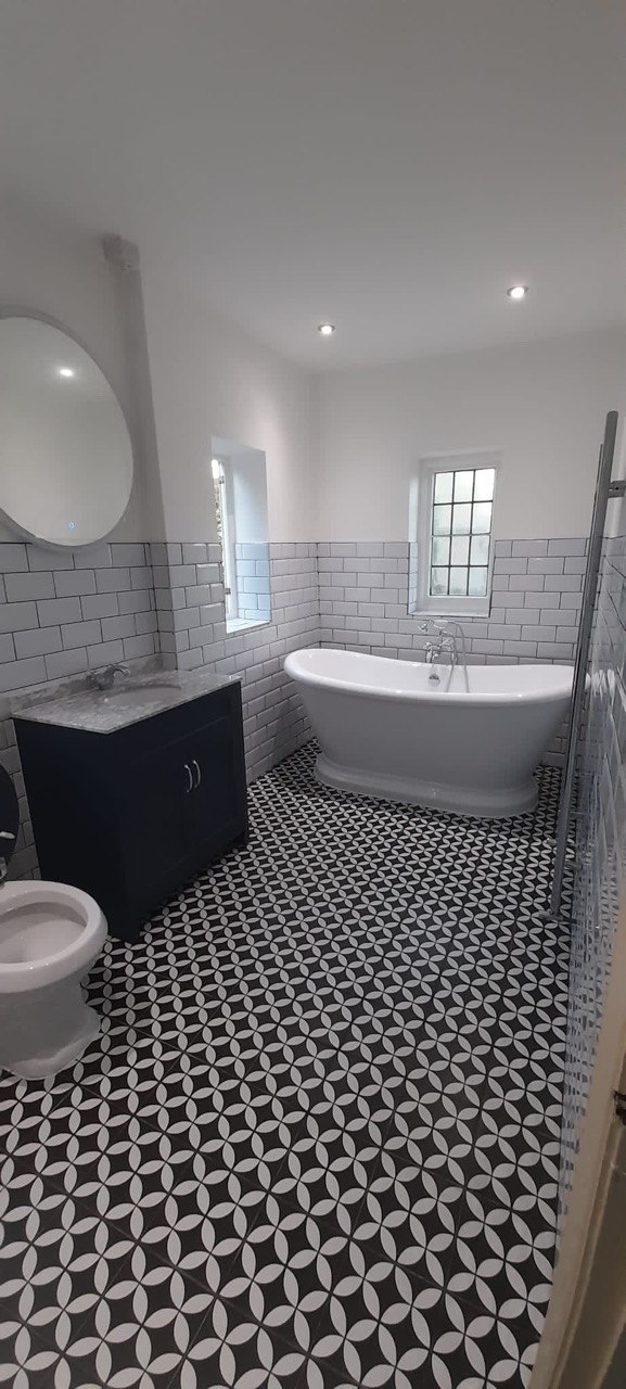 Bathroom with freestanding slipper bath, monochrome patterned floor tiles and metro wall tiles