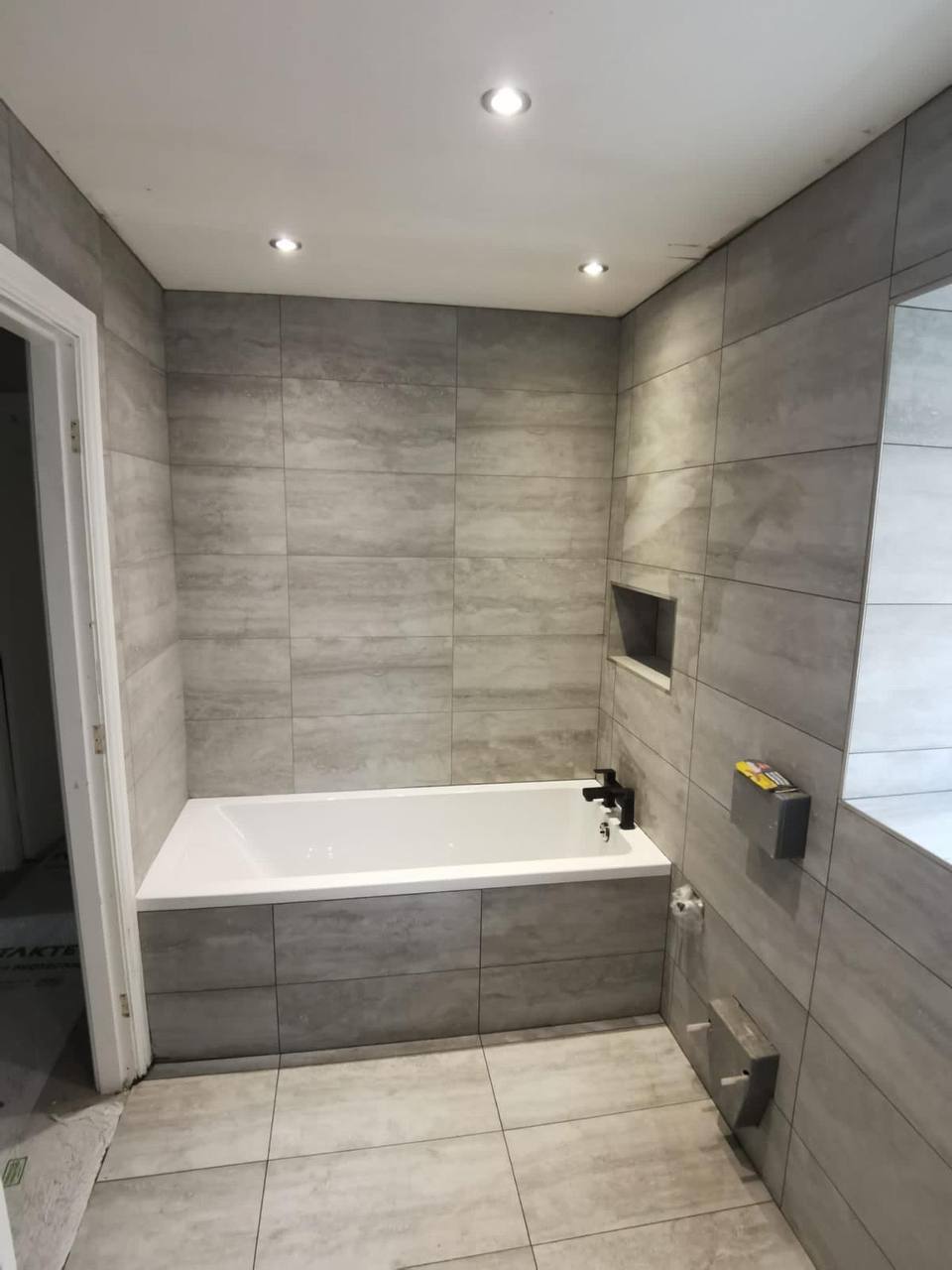 Fully tiled family bathroom with built-in bath, recessed niche and stone-effect porcelain tiles