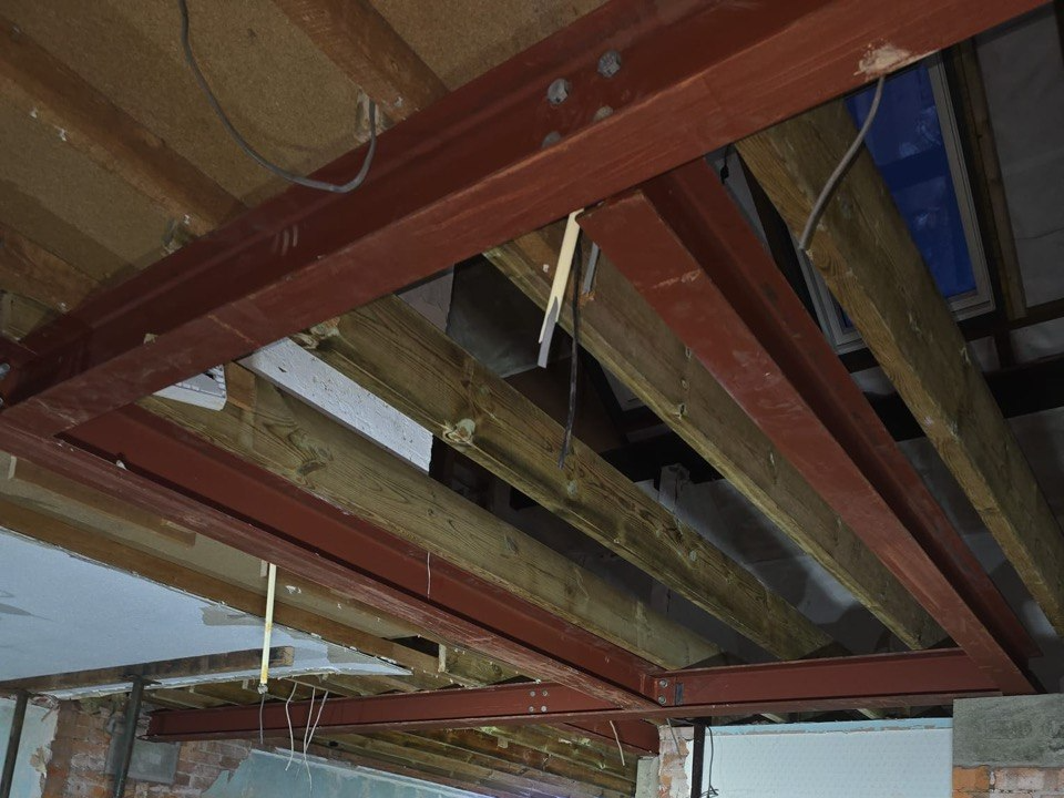 Red steel beams and new timber joists forming a reinforced floor structure