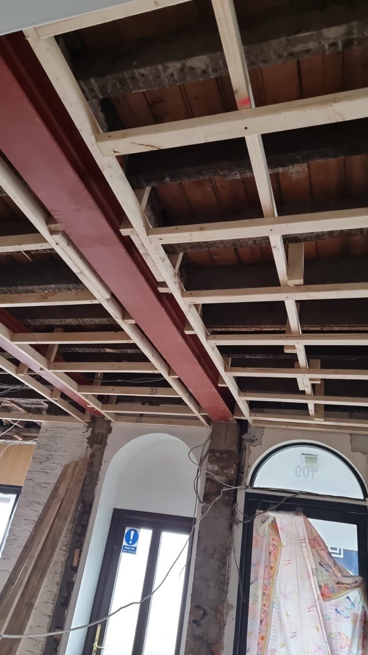 Red-oxide steel RSJ beam supporting timber floor joists during a structural alteration