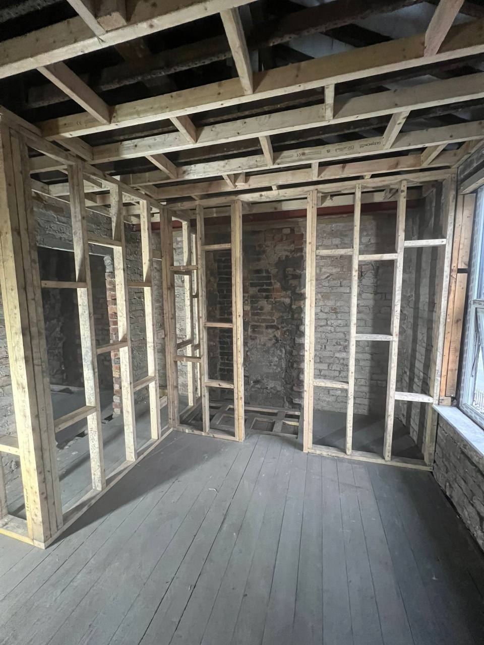 New timber stud framing built against exposed brickwork during an internal remodel